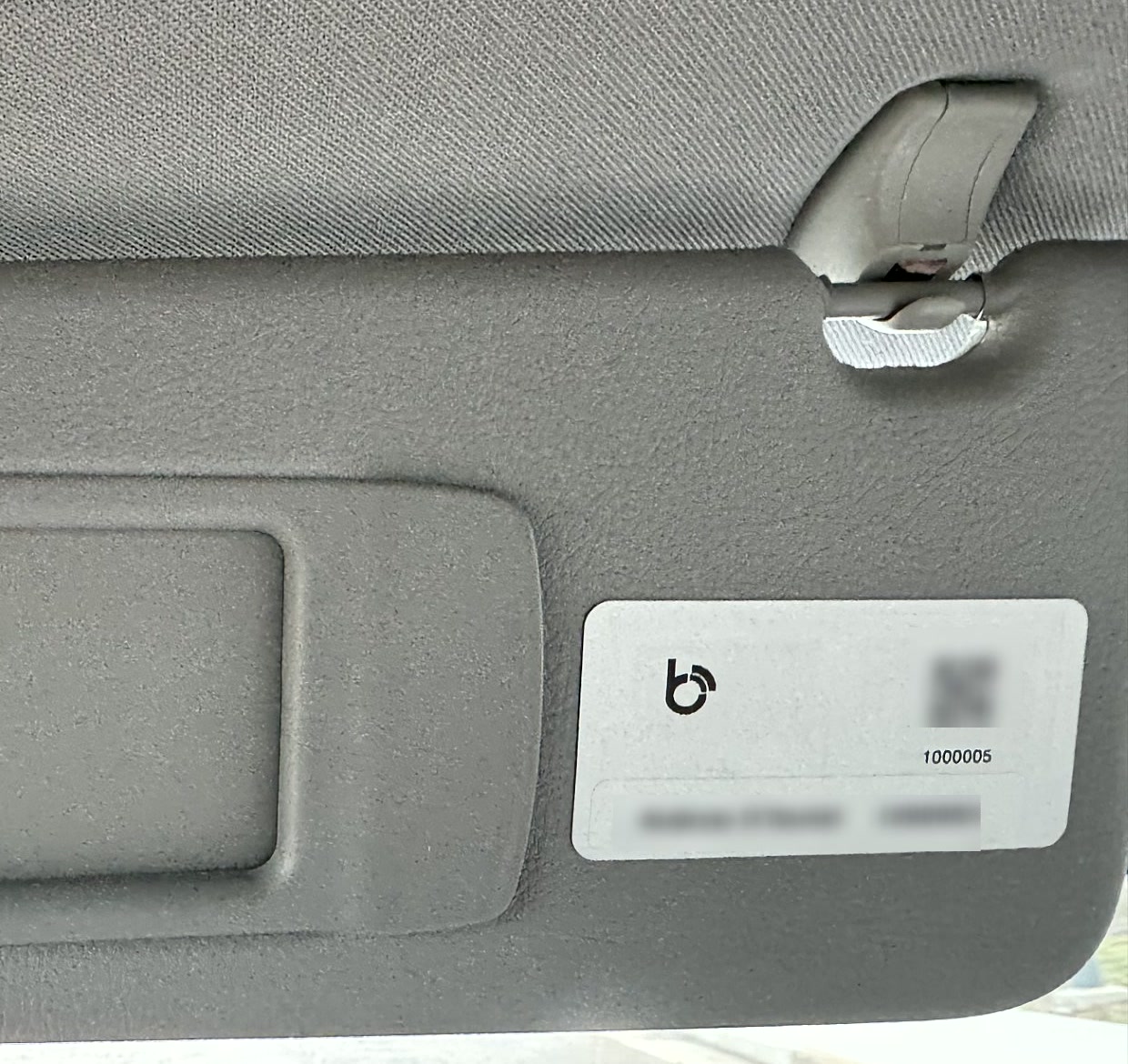 A BluSignal label applied to the sun visor of a vehicle, showing its size against the visor and mirror recess